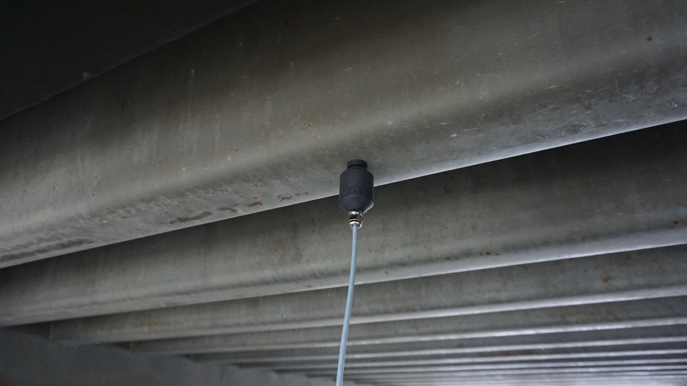 Geofón attached by its magnet to the underside of a steel beam